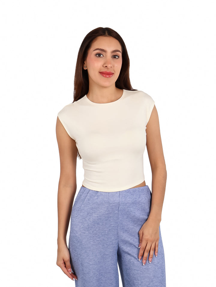 Mujer vistiendo un crop top blanco sin mangas y pantalones azules.