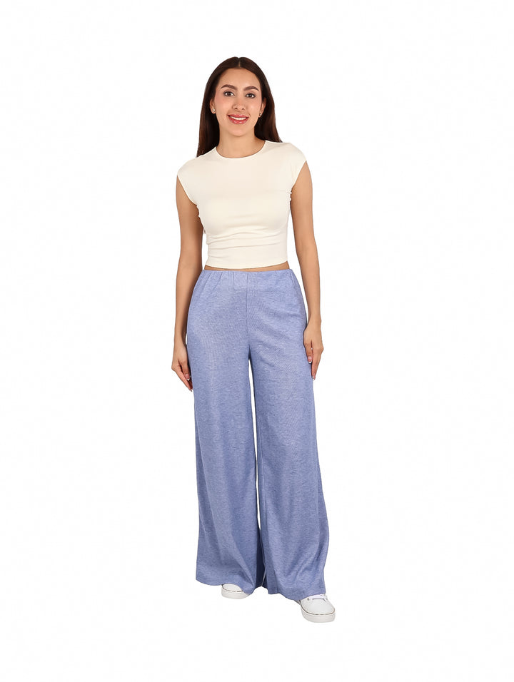 Mujer vistiendo un crop top blanco sin mangas y pantalones azules.