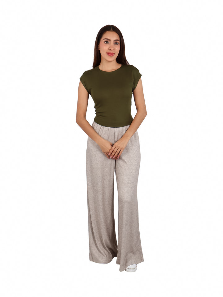 Mujer vistiendo un crop top color verde oliva de cuello redondo y pantalones grises.
