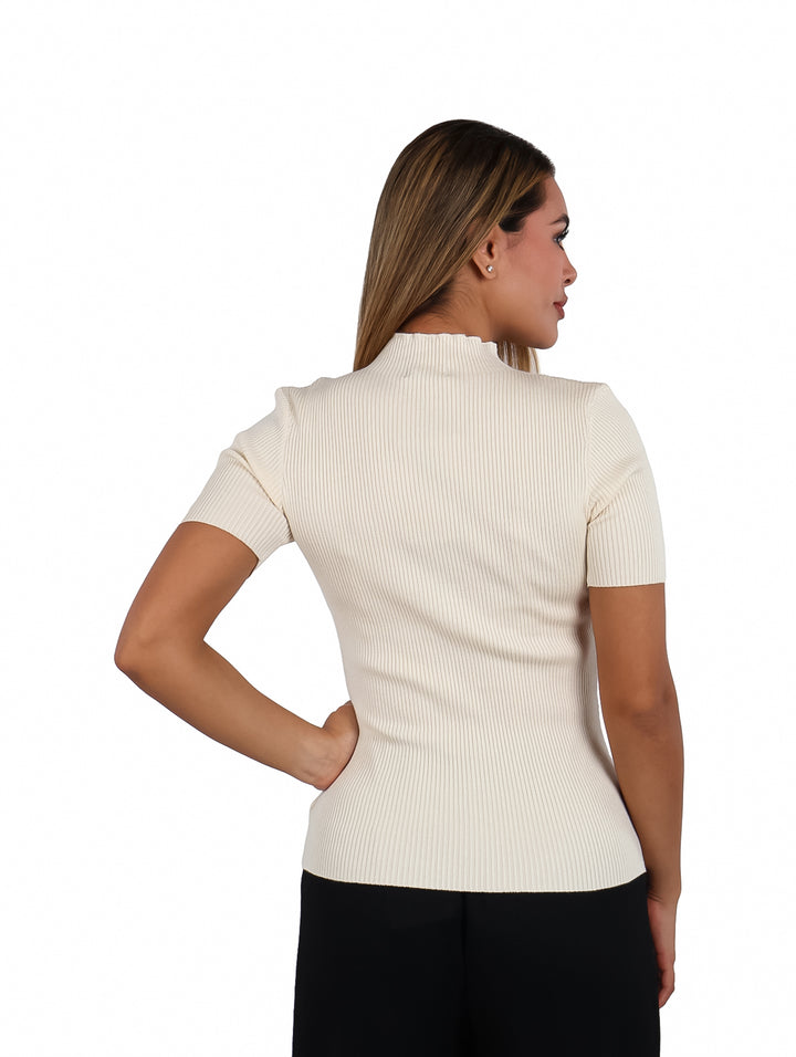 Mujer modelando blusa color ivory de cuello alto y manga corta con textura acanalada.