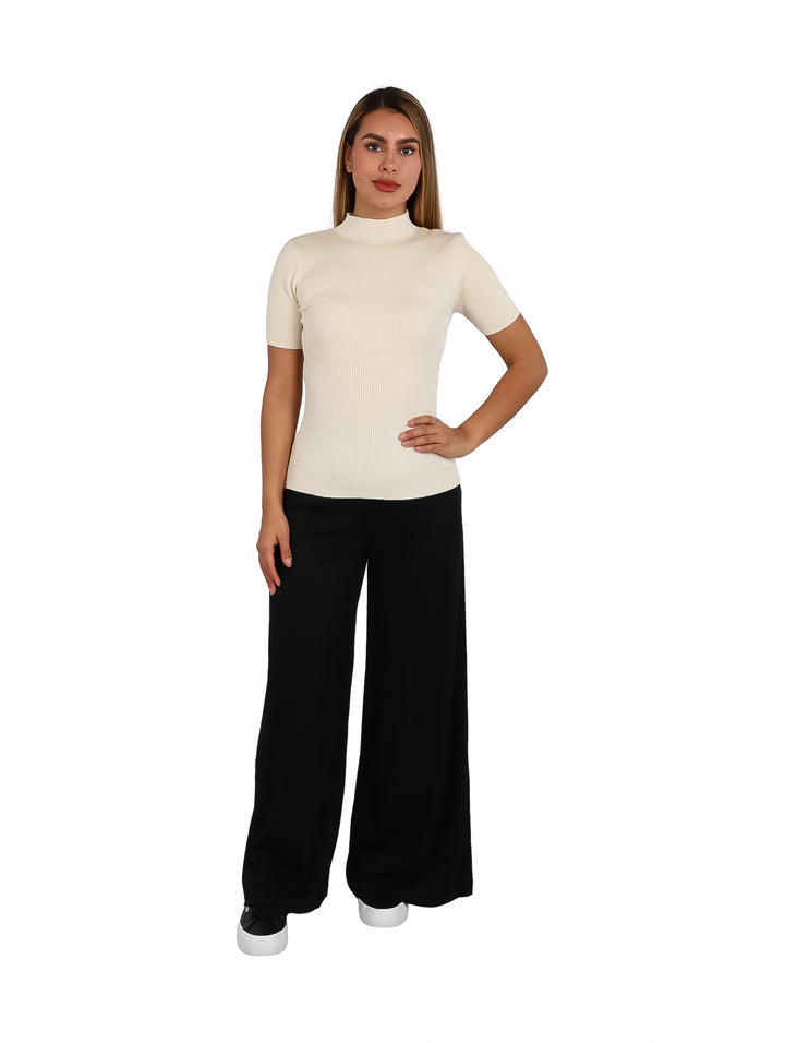 Mujer modelando blusa color ivory de cuello alto y manga corta con textura acanalada.