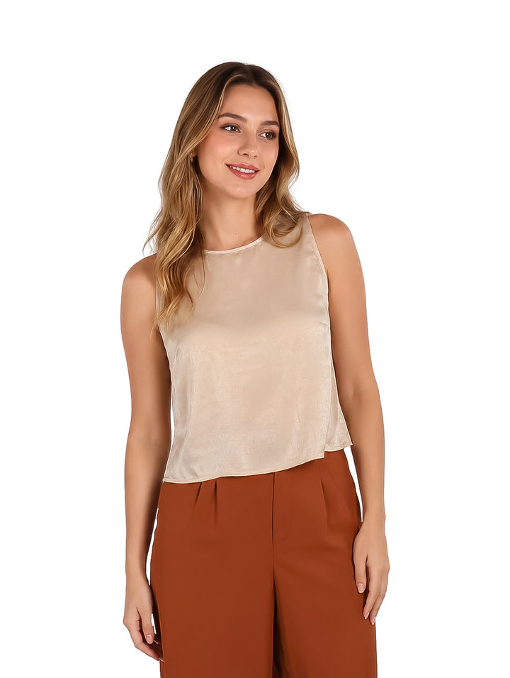 Mujer vistiendo una blusa beige sin mangas de estilo elegante.