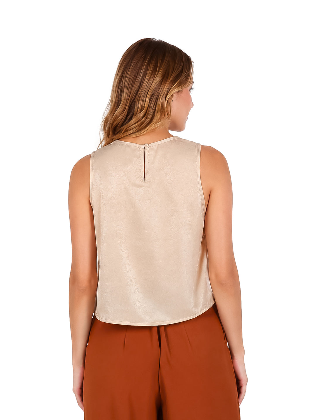 Mujer vistiendo una blusa beige sin mangas de estilo elegante.