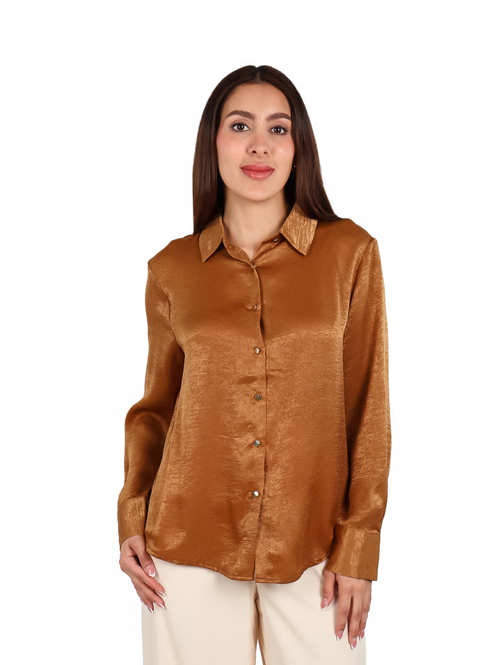 Mujer vistiendo una camisa de color café brillante con botones y manga larga.