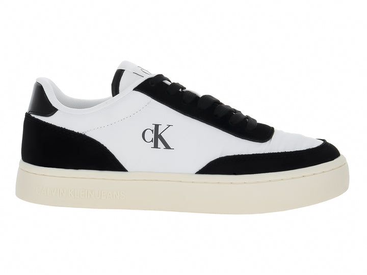 Tenis Calvin Klein de cuero color blanco con detalles en negro y suela plana blanca.