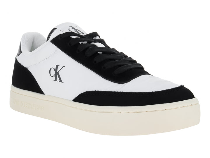 Tenis Calvin Klein de cuero color blanco con detalles en negro y suela plana blanca.
