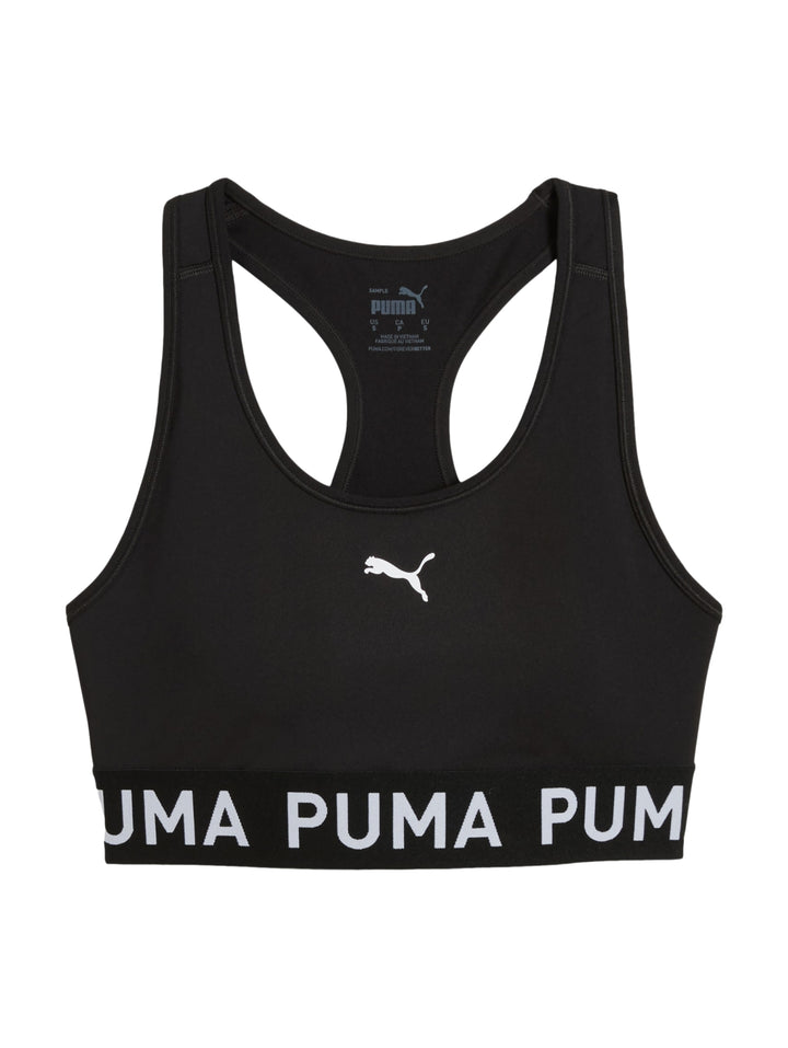 Mujer usando un bra deportivo negro de PUMA sosteniendo un balón medicinal.