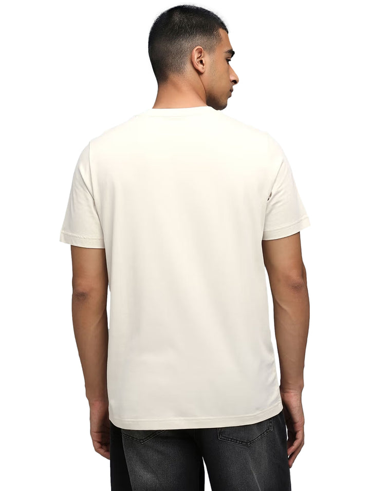 Hombre vistiendo camiseta PUMA color blanco hueso con gráfico de un tenis en el pecho.