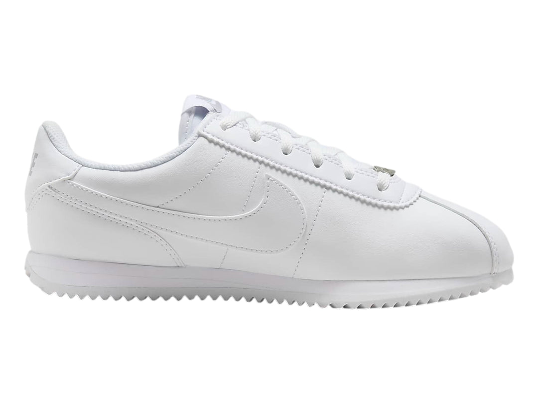 Tenis Nike Cortez blancos para niños con suela blanca y cordones.