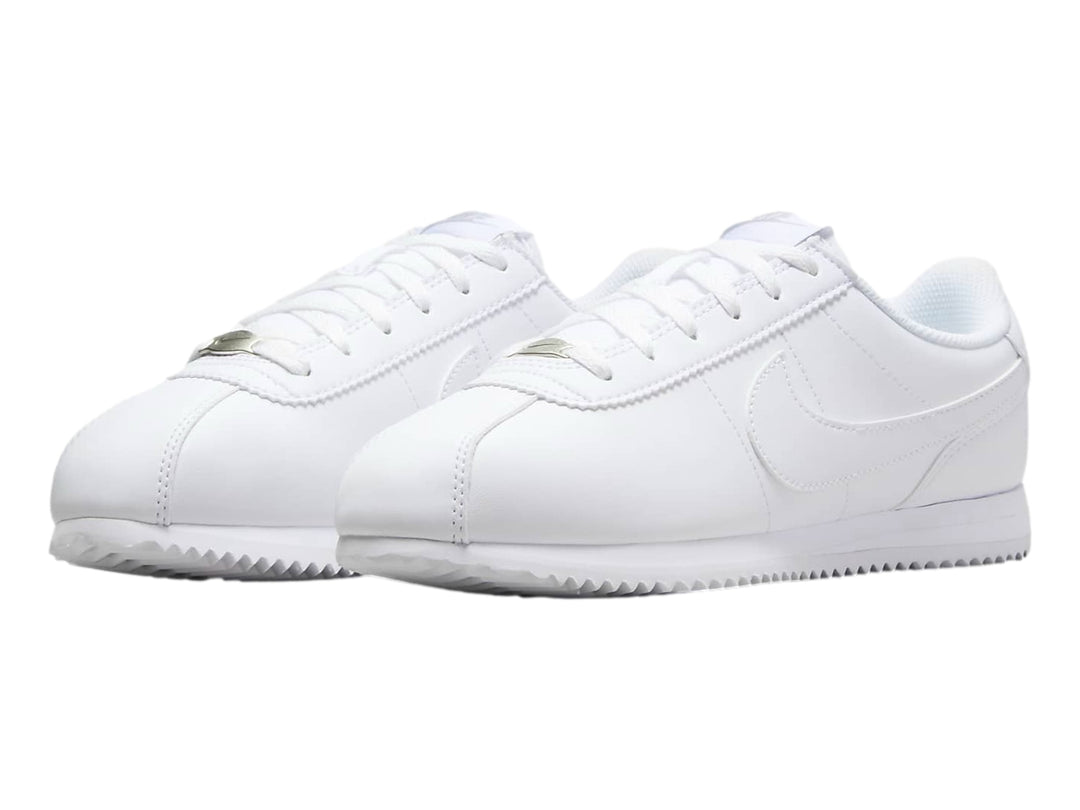Tenis Nike Cortez blancos para niños con suela blanca y cordones.