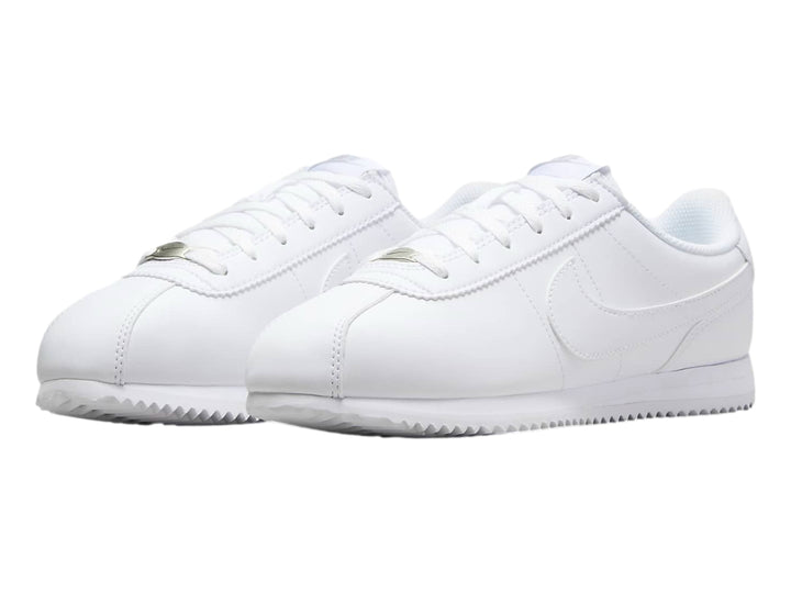 Tenis Nike Cortez blancos para niños con suela blanca y cordones.