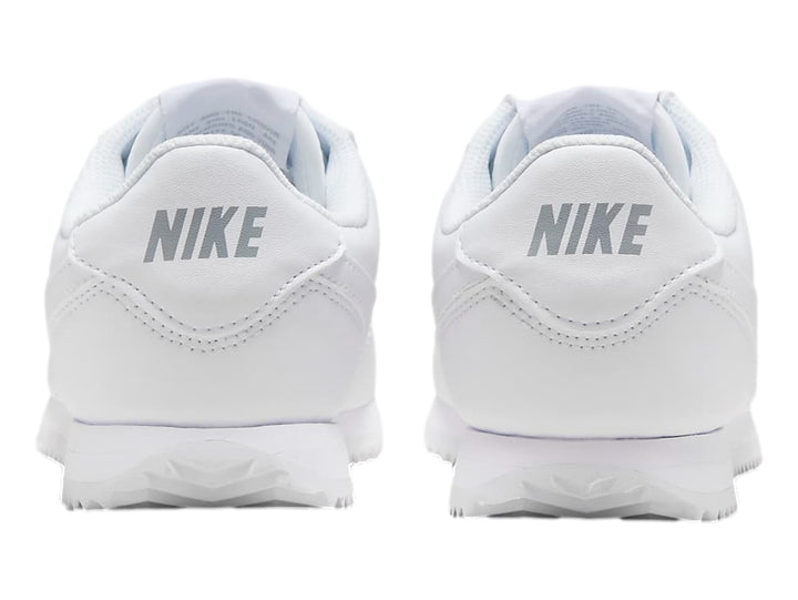 Tenis Nike Cortez blancos para niños con suela blanca y cordones.