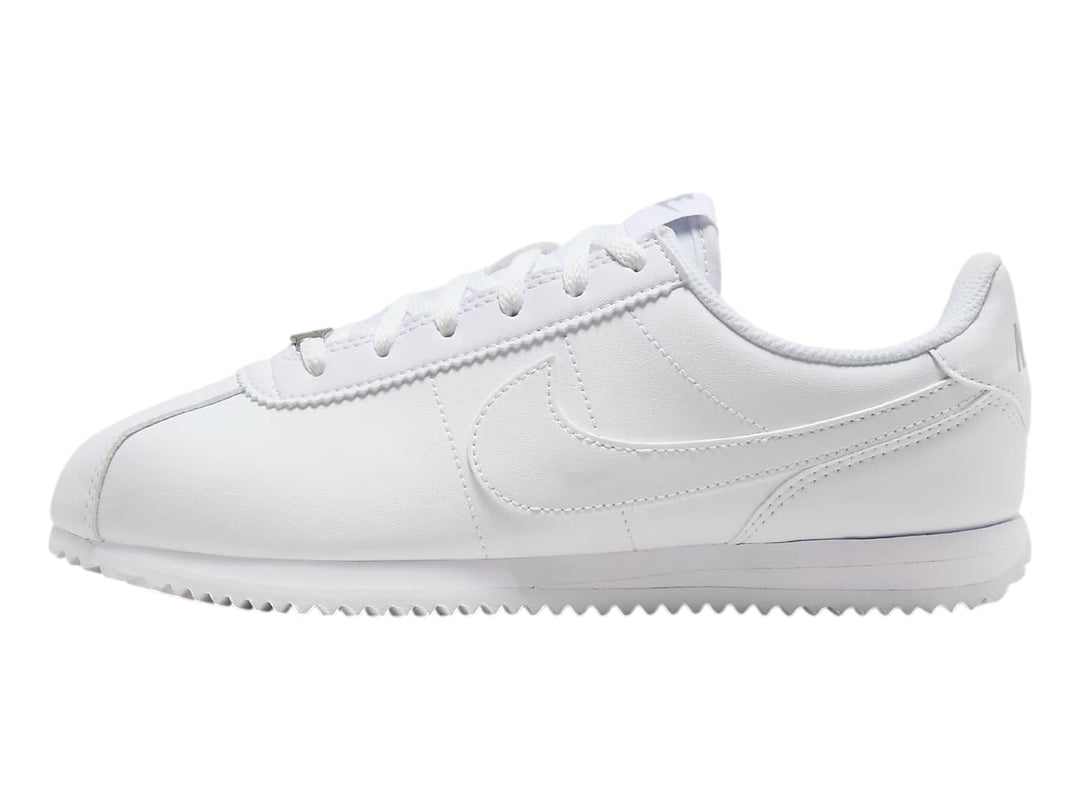 Tenis Nike Cortez blancos para niños con suela blanca y cordones.