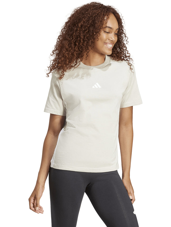 Mujer vistiendo playera Adidas color beige de manga corta y cuello redondo.
