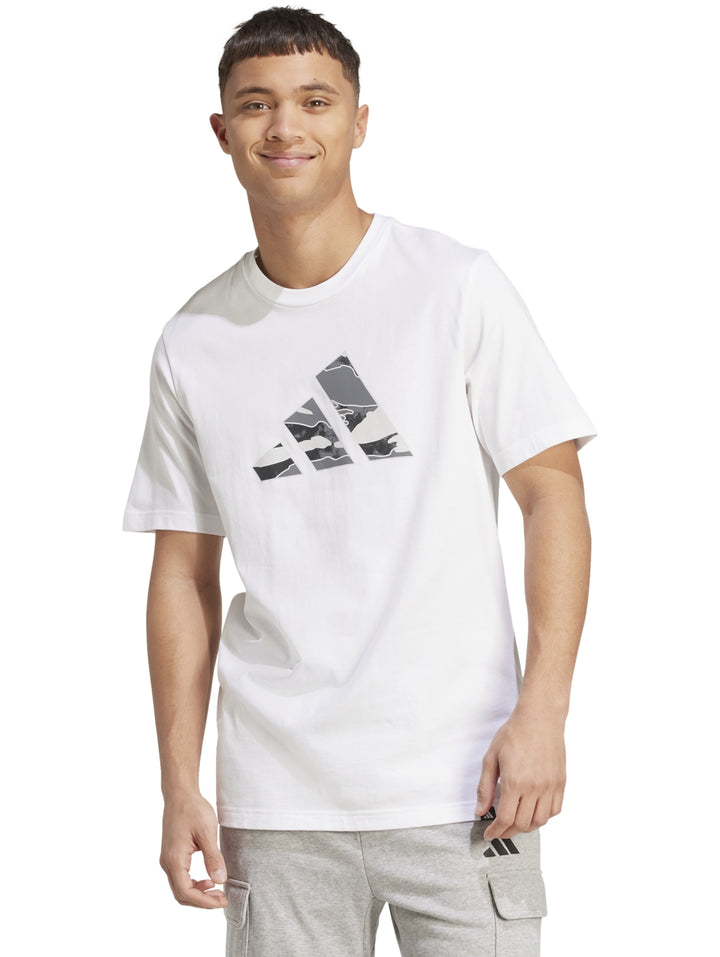 Hombre vistiendo playera blanca Adidas con logo gráfico camuflado en el pecho.