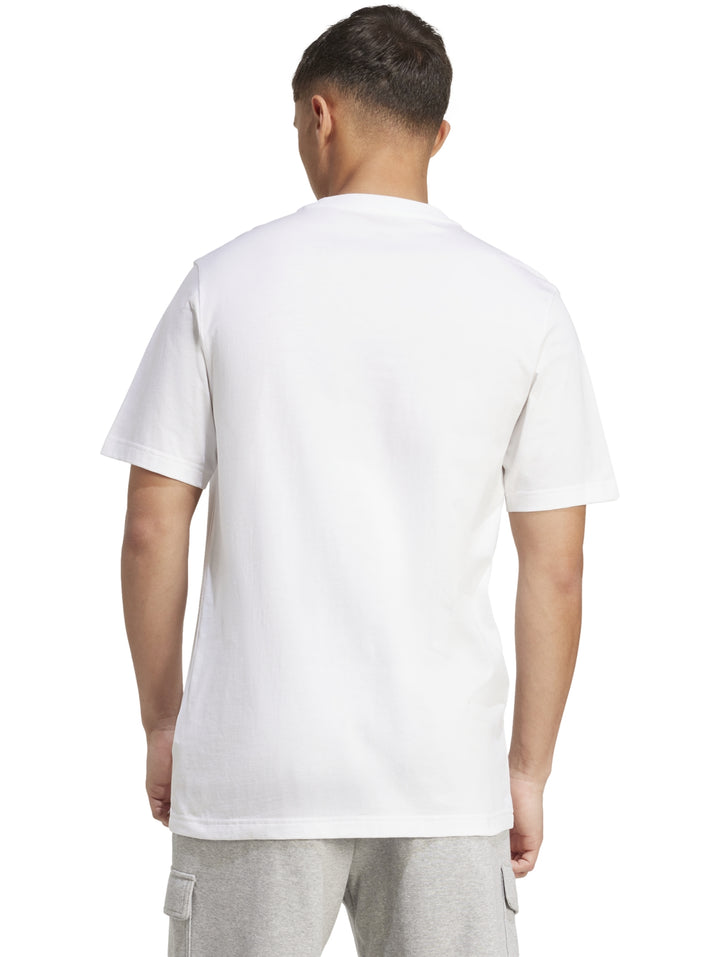 Hombre vistiendo playera blanca Adidas con logo gráfico camuflado en el pecho.