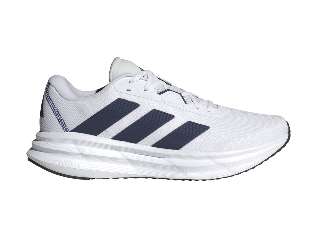 Tenis Adidas Galaxy 7 en color blanco con tres franjas azul oscuro y suela blanca amortiguada.