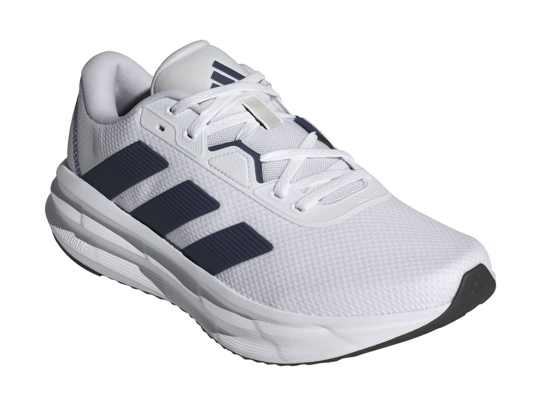 Tenis Adidas Galaxy 7 en color blanco con tres franjas azul oscuro y suela blanca amortiguada.