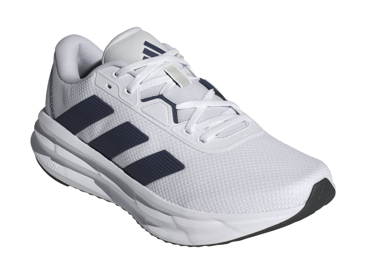 Tenis Adidas Galaxy 7 en color blanco con tres franjas azul oscuro y suela blanca amortiguada.