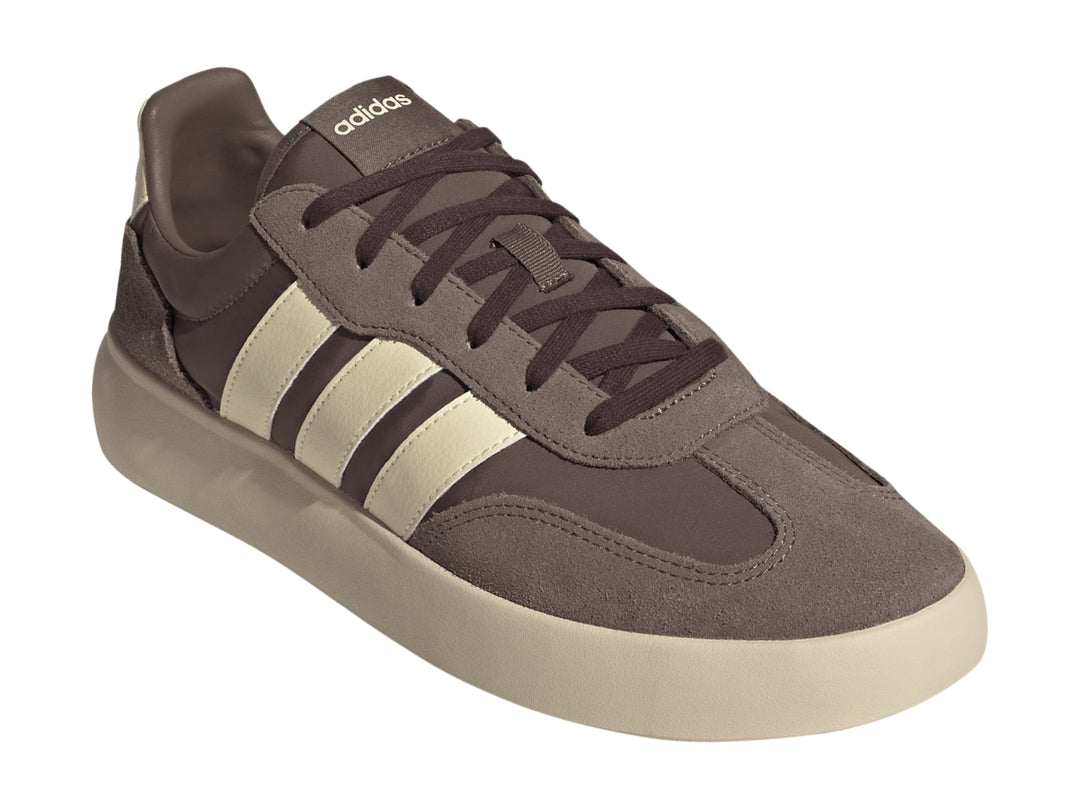 Tenis Adidas color marrón con tres franjas y suela gruesa en color crema, vista lateral.