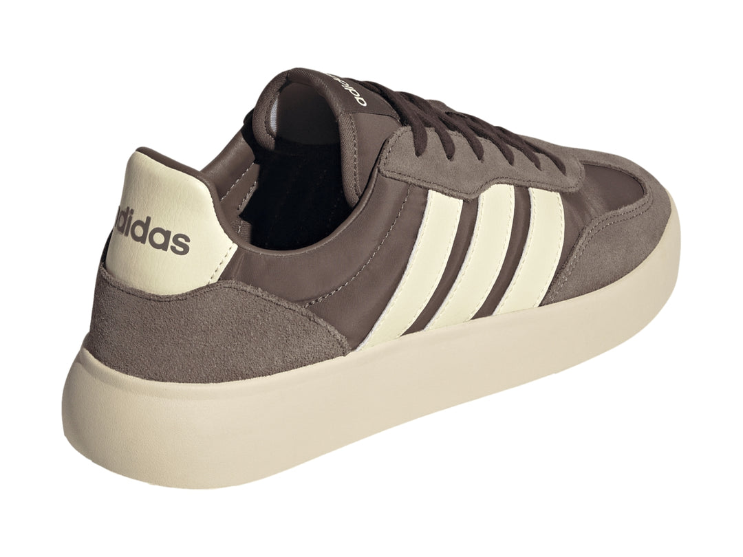 Tenis Adidas color marrón con tres franjas y suela gruesa en color crema, vista lateral.
