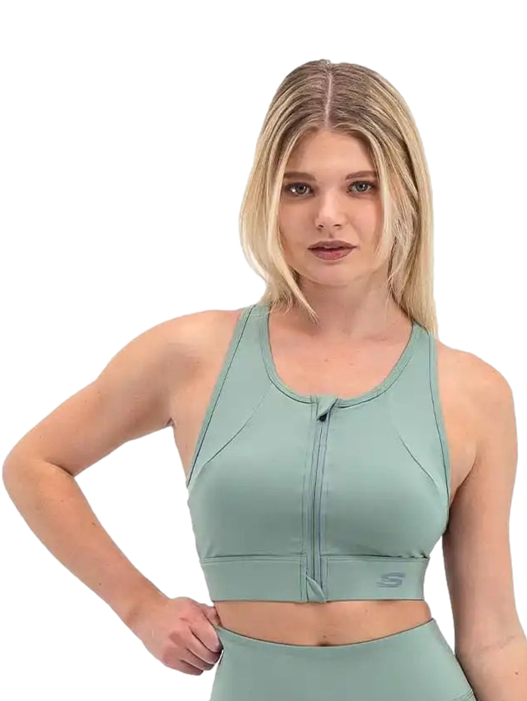 Mujer vistiendo un top deportivo corto color verde claro con cierre frontal de la marca Skechers.
