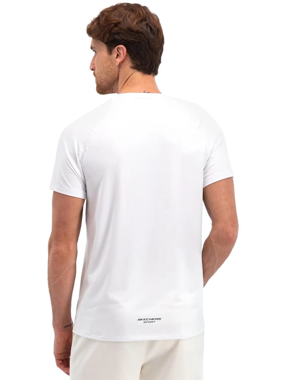 Hombre vistiendo una playera deportiva blanca de manga corta marca Skechers.