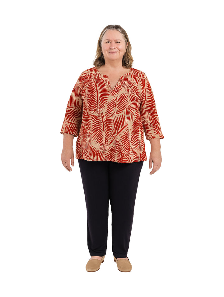 Mujer con blusa roja estampada de manga corta y pantalones negros.