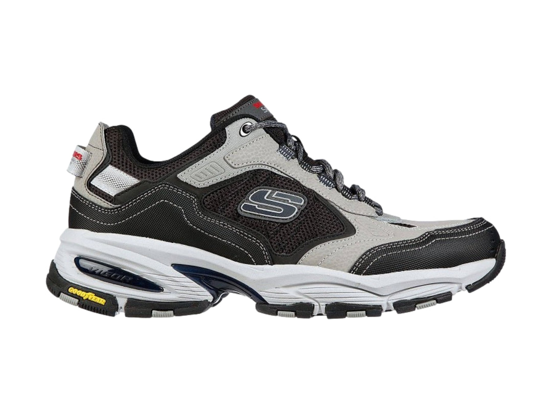 Tenis deportivos Skechers Vigor 3.0 en colores gris y negro con suela blanca y detalles amarillos.