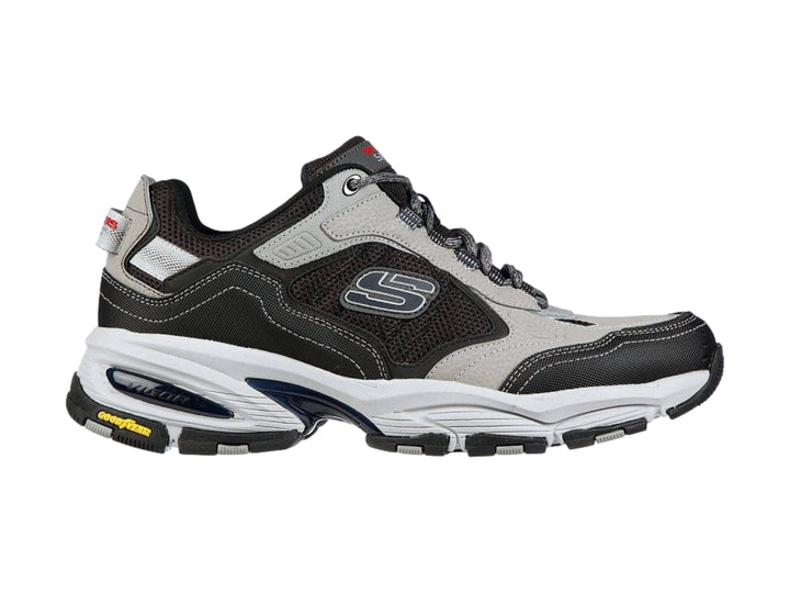 Tenis deportivos Skechers Vigor 3.0 en colores gris y negro con suela blanca y detalles amarillos.