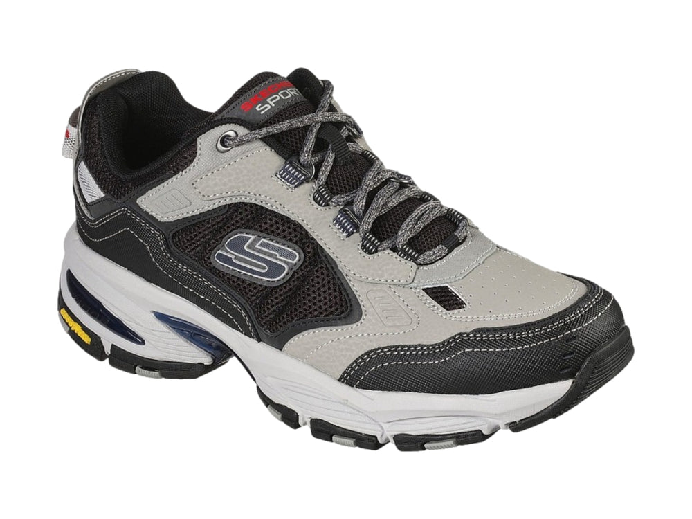 Tenis deportivos Skechers Vigor 3.0 en colores gris y negro con suela blanca y detalles amarillos.