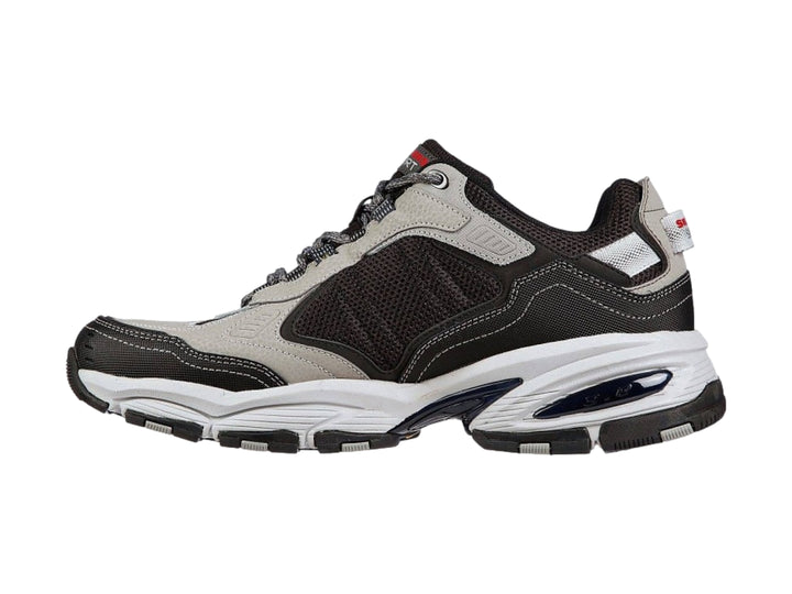 Tenis deportivos Skechers Vigor 3.0 en colores gris y negro con suela blanca y detalles amarillos.