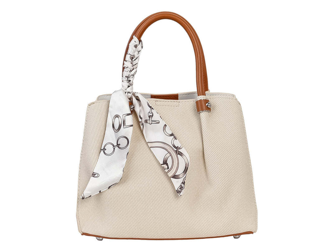 Bolso de mano color beige con asa marrón y un pañuelo blanco con estampado negro anudado al asa.