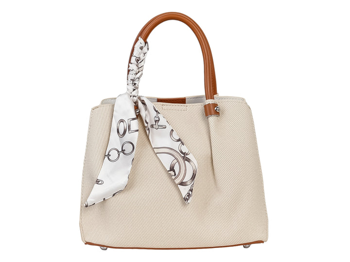 Bolso de mano color beige con asa marrón y un pañuelo blanco con estampado negro anudado al asa.