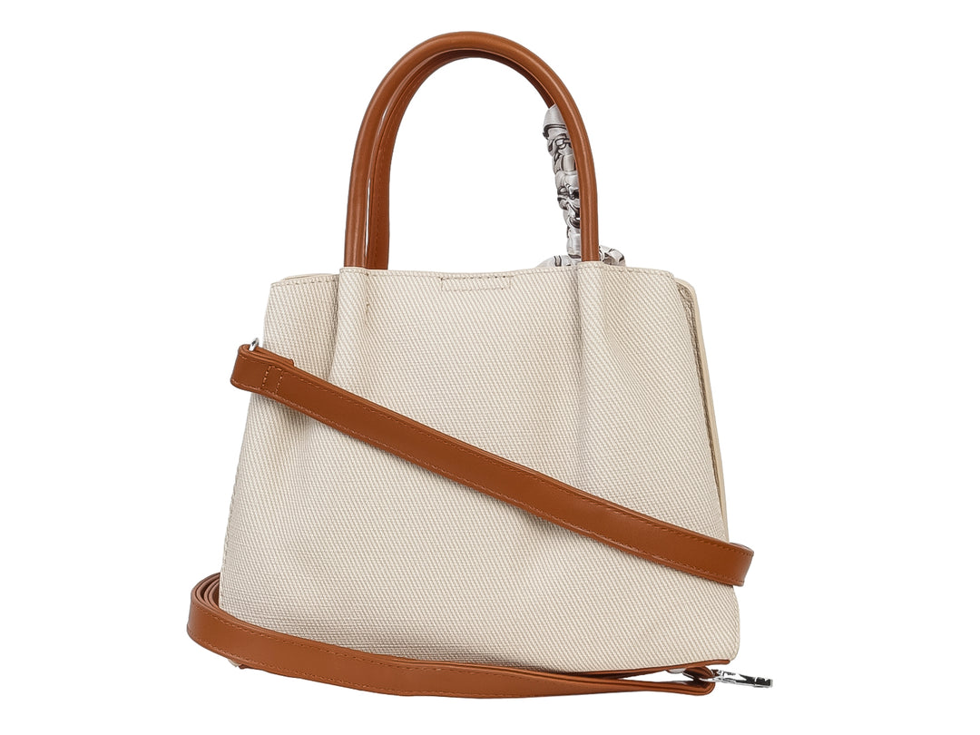 Bolso de mano color beige con asa marrón y un pañuelo blanco con estampado negro anudado al asa.