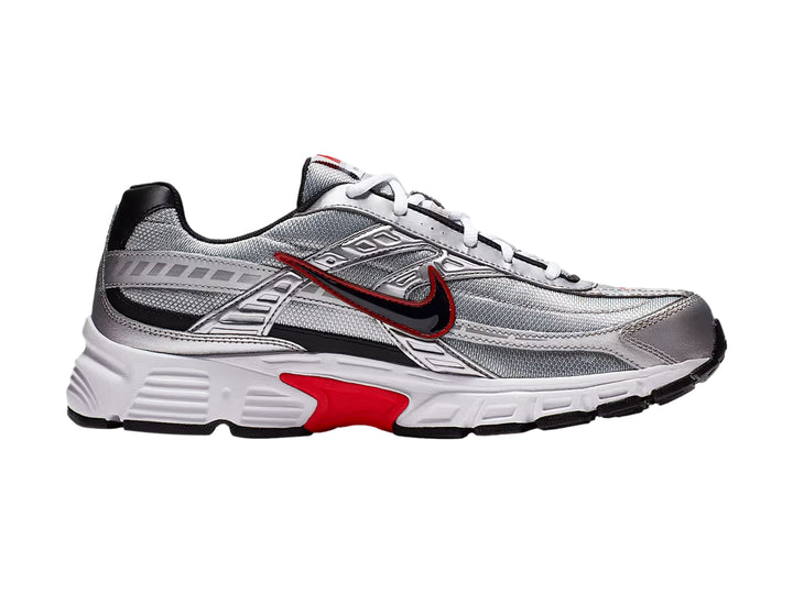 Tenis Nike Initiator en color plata metálico con detalles en rojo y negro y suela blanca.