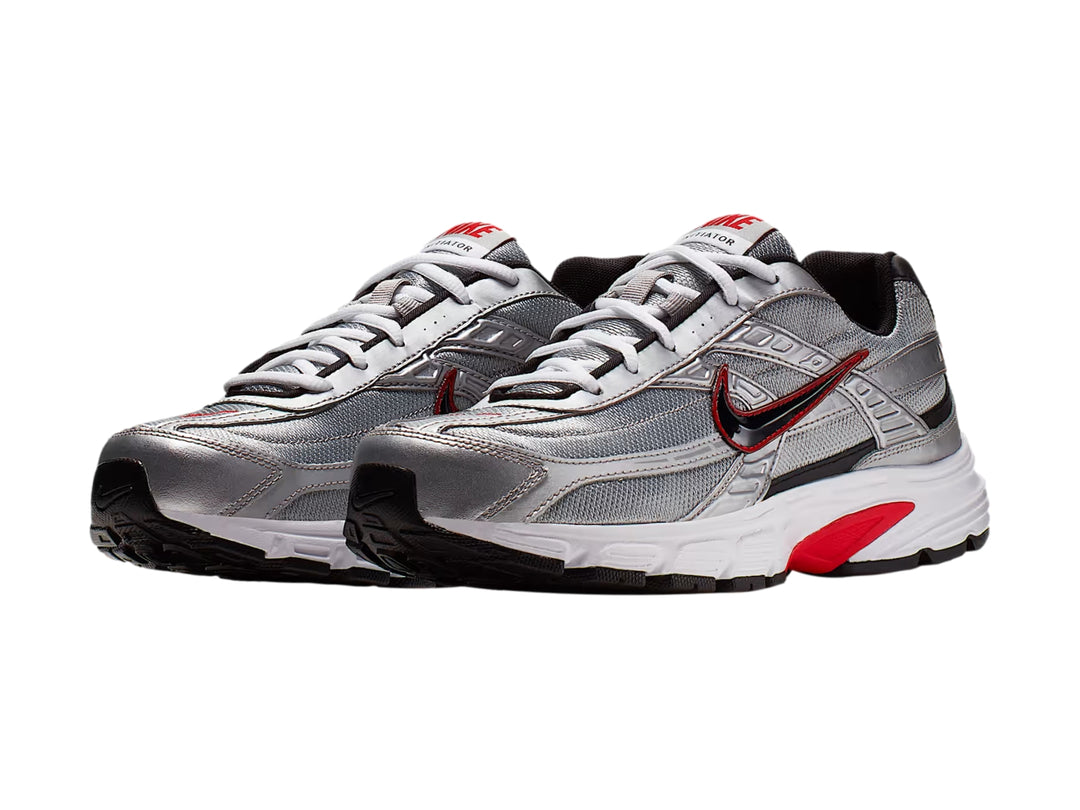 Tenis Nike Initiator en color plata metálico con detalles en rojo y negro y suela blanca.