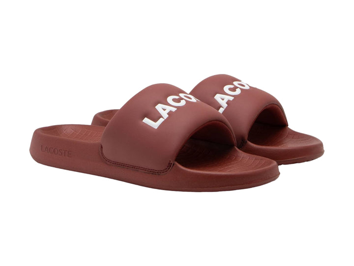 Sandalia slide Lacoste color borgoña con logotipo blanco en la banda superior.