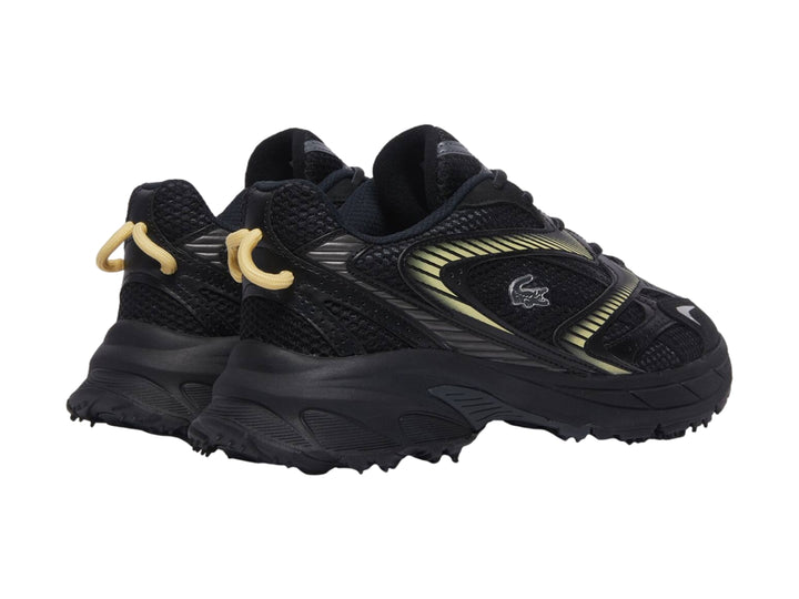 Tenis deportivos Lacoste color negro con detalles en amarillo y suela gruesa.