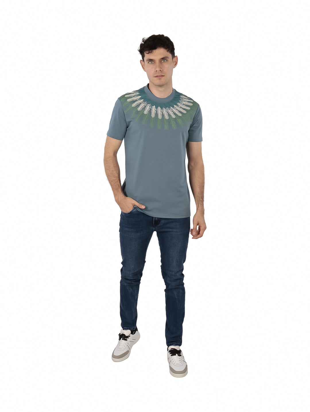 Hombre vistiendo playera color teal con estampado decorativo blanco y verde alrededor del cuello.