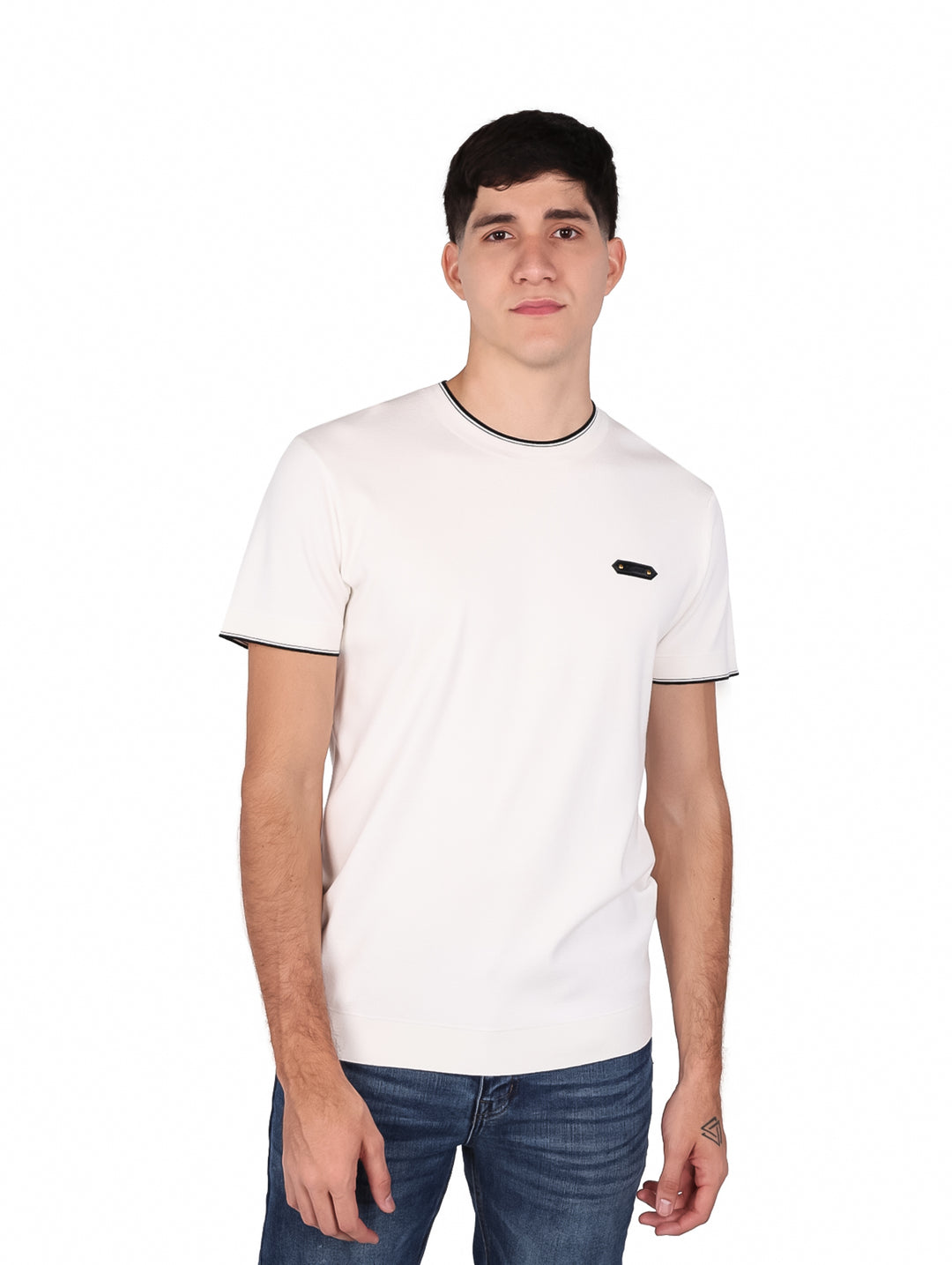 Hombre vistiendo playera blanca de manga corta con ribete negro en el cuello y las mangas.