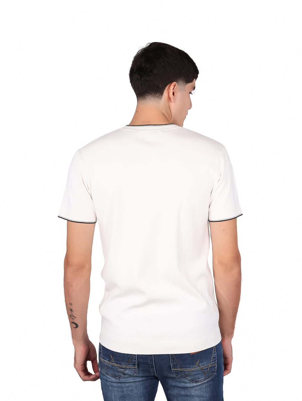 Hombre vistiendo playera blanca de manga corta con ribete negro en el cuello y las mangas.