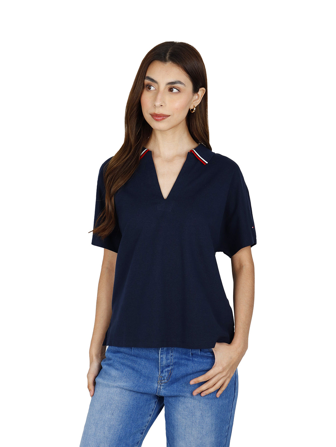 Mujer vistiendo polo Tommy Hilfiger color azul marino con detalles rojos y blancos en el cuello y jeans azules.
