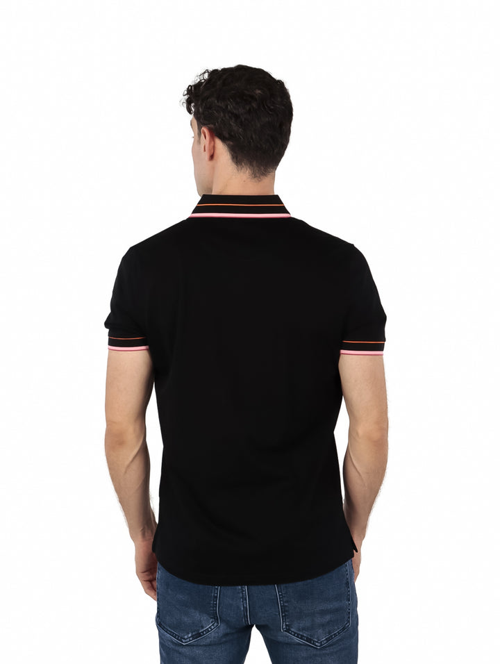 Hombre vistiendo polo Givenchy color negro con detalles en rosa en el cuello y mangas.