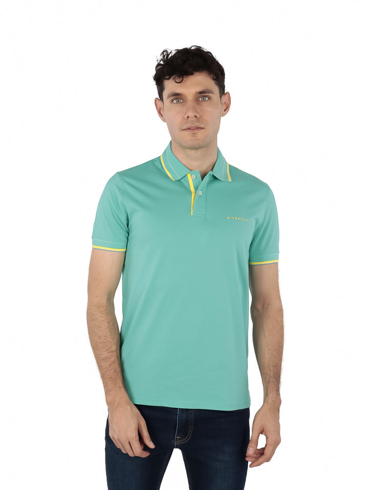Hombre vistiendo polo Givenchy color turquesa con detalles amarillos en el cuello y los bordes de las mangas.