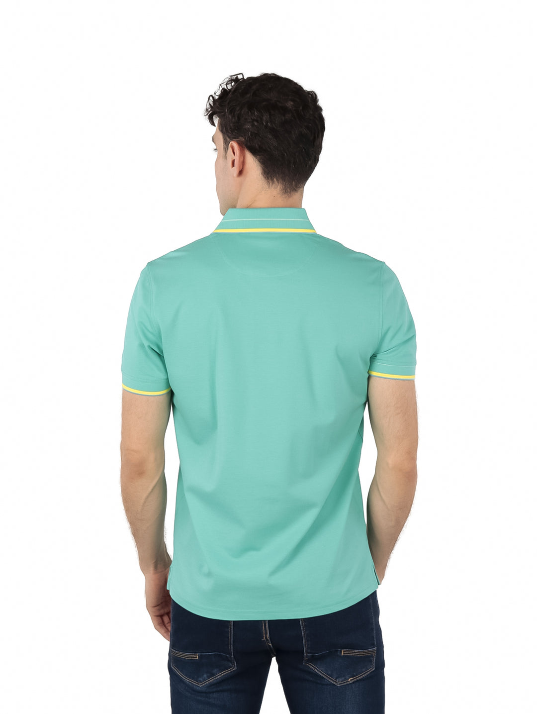 Hombre vistiendo polo Givenchy color turquesa con detalles amarillos en el cuello y los bordes de las mangas.