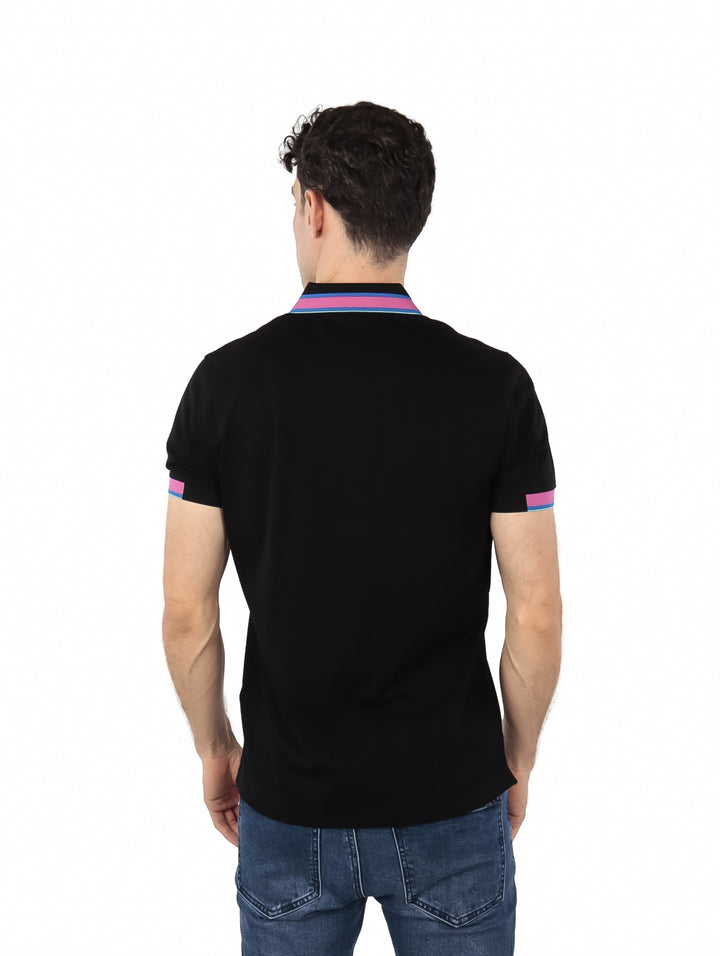 Hombre vistiendo polo negro de Givenchy con detalles en rosa y azul en el cuello y mangas.