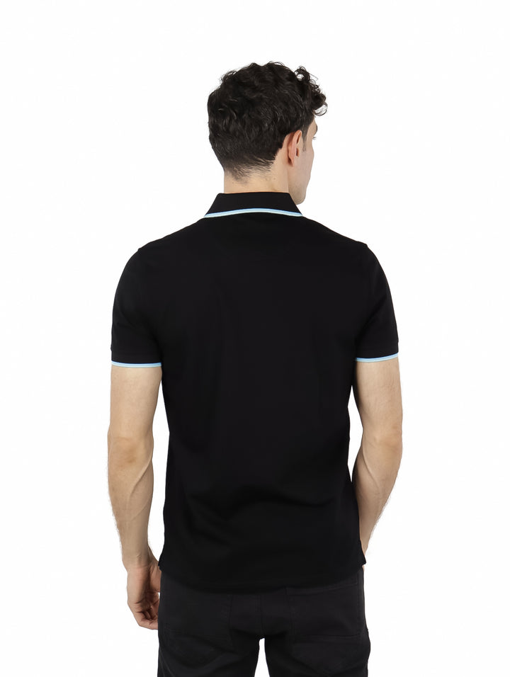 Hombre vistiendo polo negro Givenchy con detalles en celeste en cuello y mangas.