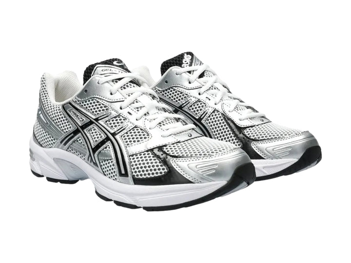 Tenis deportivos ASICS GEL-1130 color blanco y plateado con detalles negros y malla transpirable.