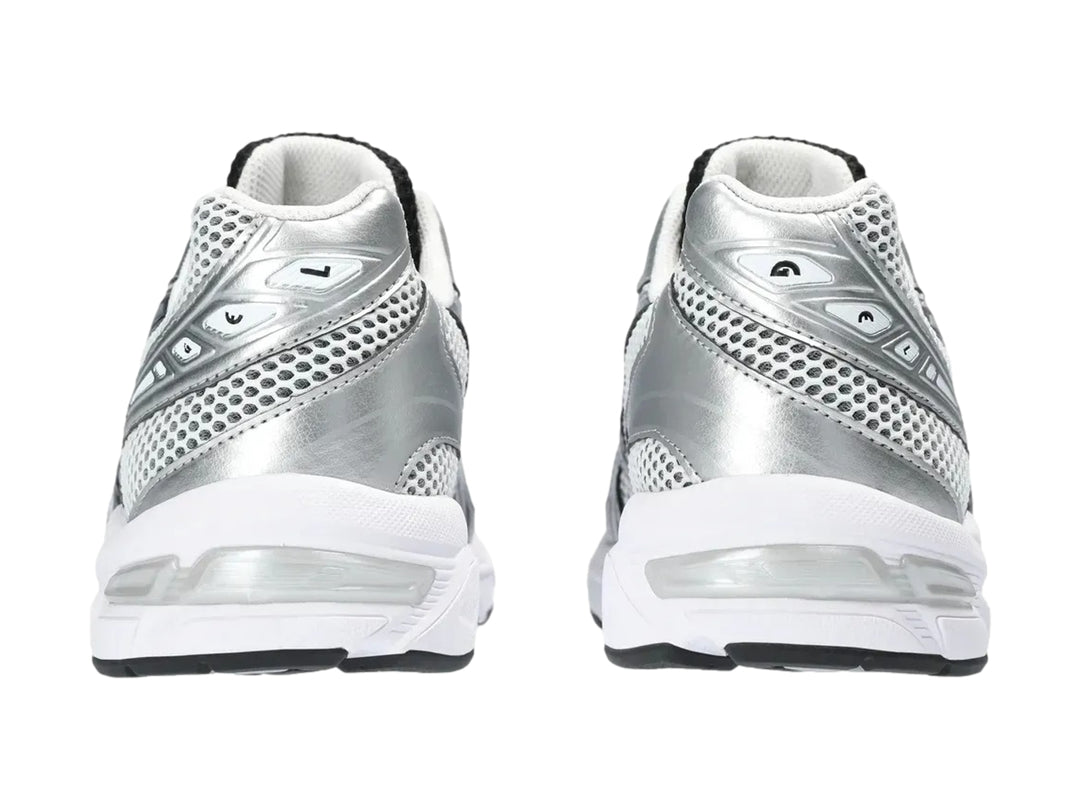 Tenis deportivos ASICS GEL-1130 color blanco y plateado con detalles negros y malla transpirable.
